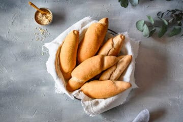 elbstgemachte Grahamweckerl in einem Korb mit weißen Leinentuch, von oben