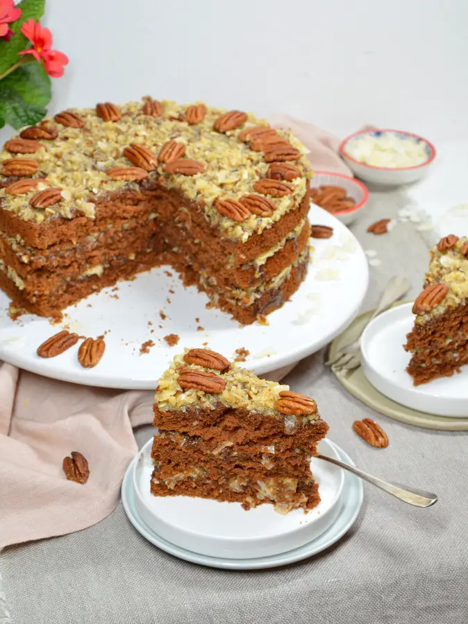 German Chocolate Cake, 2 Stücke sind herausgeschnitten und auf Tellern, im Hintergrund der Kuchen
