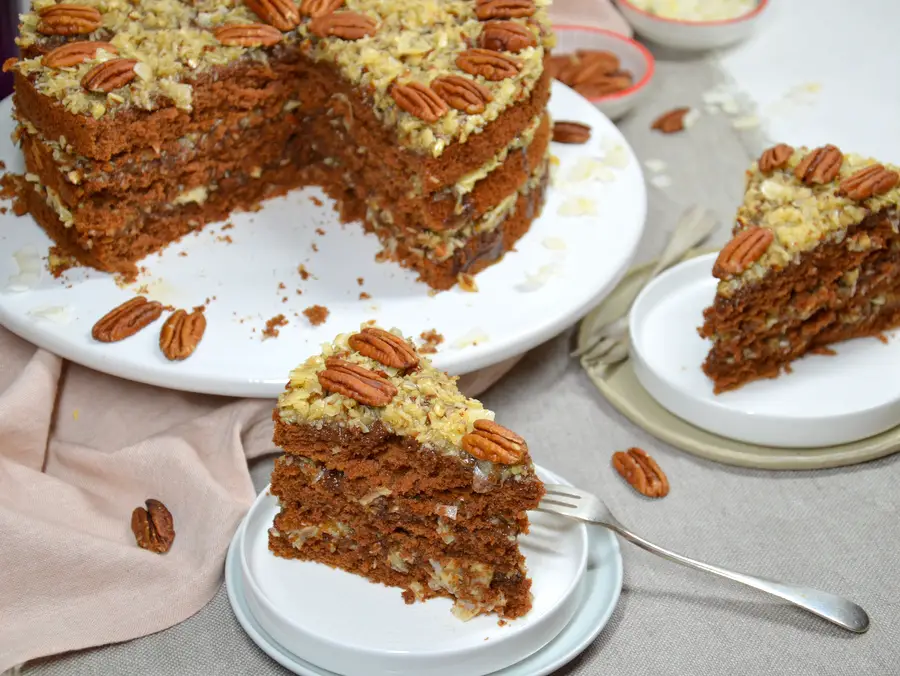 German Chocolate Cake, 2 Stücke sind herausgeschnitten und auf Tellern, im Hintergrund der Kuchen