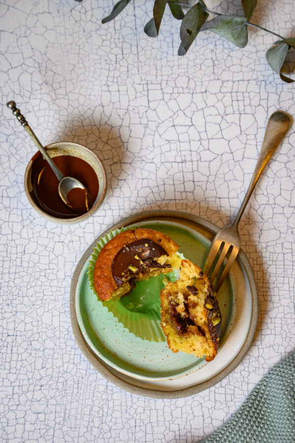 Muffins mit Pistazienmus auf einem kleinen Teller, mit Gabel in 2 Hälften geteilt
