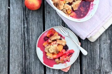 Früchte Crumble mit Walnussstreuseln in einer Form auf Holzbrettern, von oben