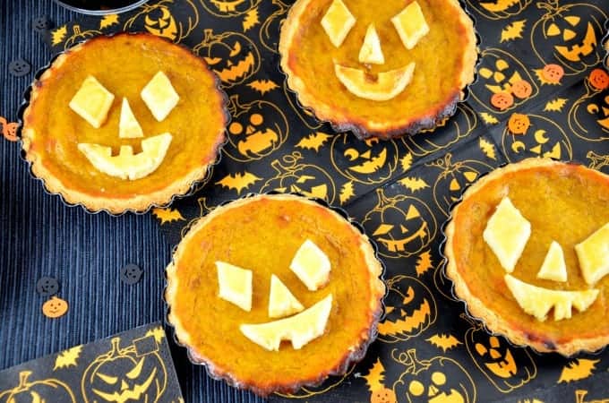 Halloween-Tartelettes mit Kürbis auf schwarz-orangen Servietten, von oben