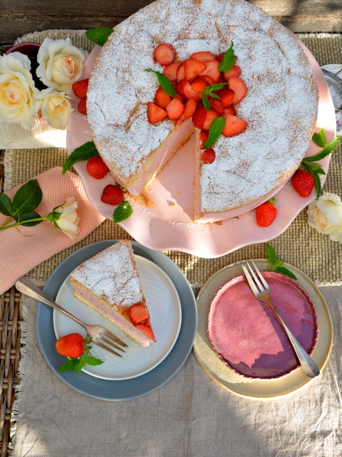 Erdbeer-Käsesahne-Torte von oben, vorne 1 Stück auf Teller, hinten die Torte