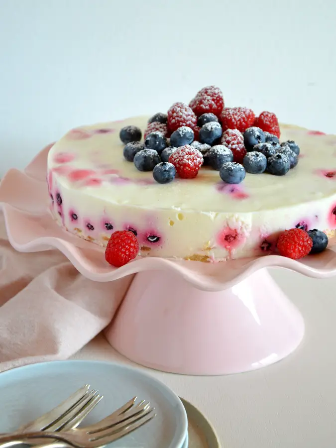Joghurttorte mit Beerenmischung. auf rosa Tortenplatte
