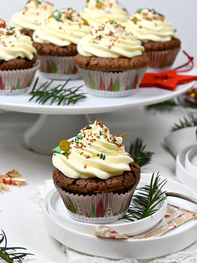 Weihnachtliche Schoko-Cupcakes mit Frischkäse Topping und Zuckerstreusel, 1 Cupcake auf Teller