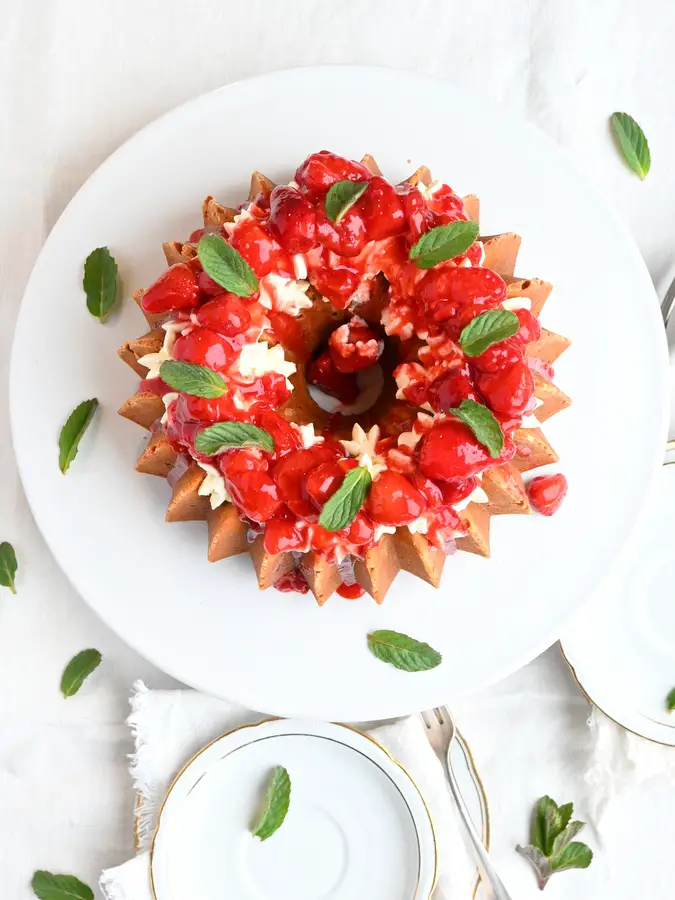 Topfengugelhupf mit Erdbeeren und Schlagrahm auf Tortenplatte, von oben