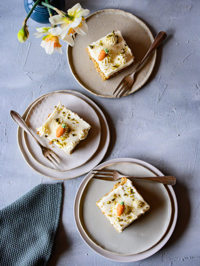 3 Stück Karotten-Mohn-Blechkuchen mit Mascarpone-Topping auf Tellern, von oben aufgenommen