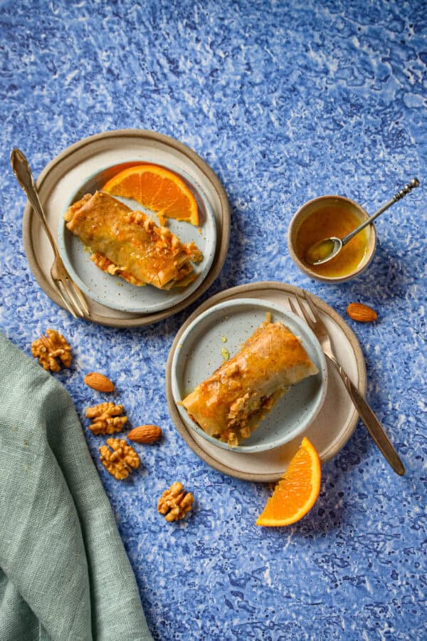Selbstgemachte Baklava mit Orangensirup, 2 Stück auf Tellern auf blauem Untergrund, von oben