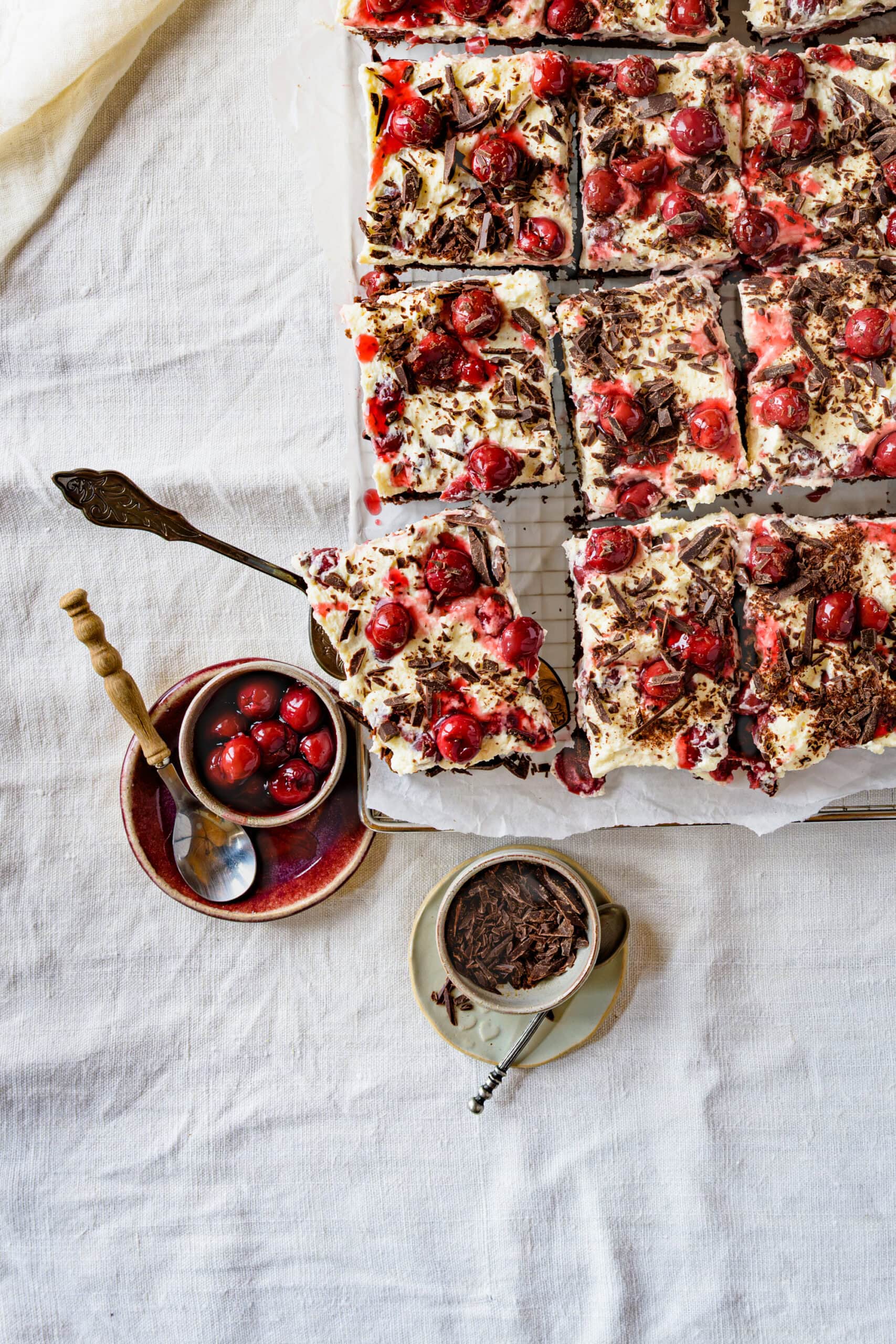 Schwarzwälder Kirschtorte vom Blech auf einem Backgitter, 1 Stück wird gerade herausgehoben, von oben