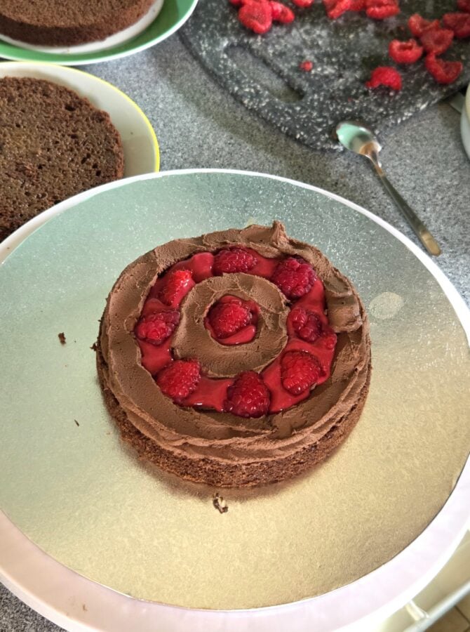 Schokoladentorte wird geschichtet, mit Schokoladenganahce, Himbeercurd und Himbeeren