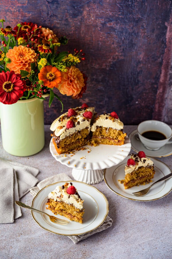 Kaffeebuttercremetorte mit Pekan-Salzkaramell, vorne 2 Stück auf Tellern, im Hintergrund ein bunter Blumenstrauß
