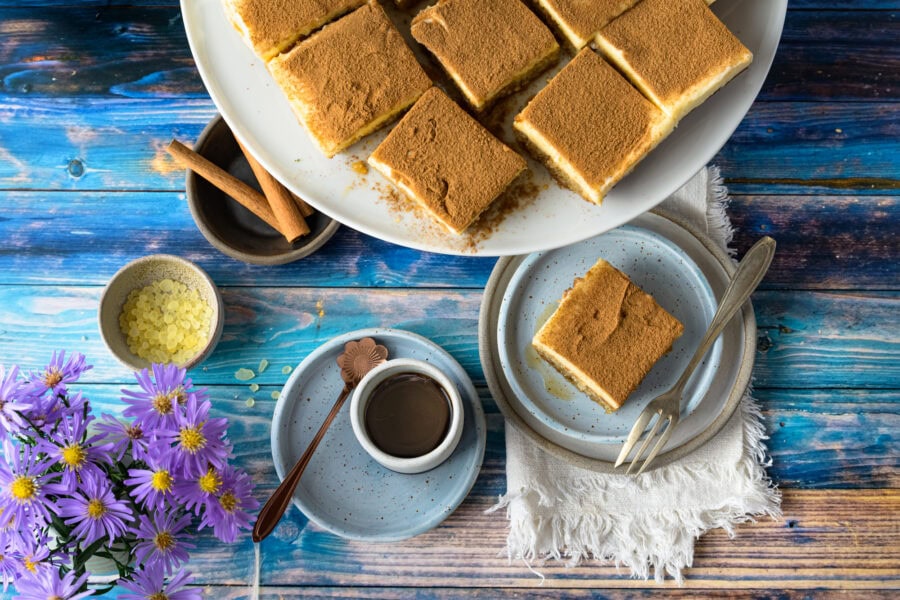 Politiko Dessert: Griechischer Grießkuchen mit Zimt in quadratische Stücke geschnitten auf Tortenplatte und Teller, von oben
